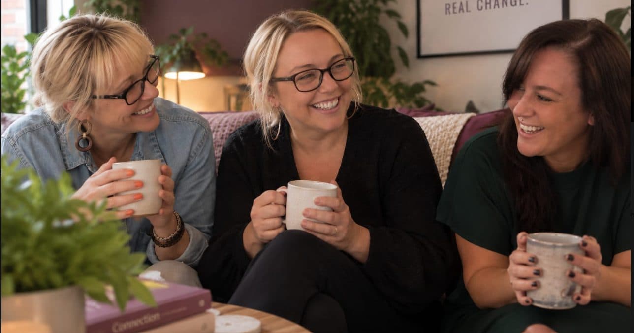 Three women sharing a laugh over cups of tea