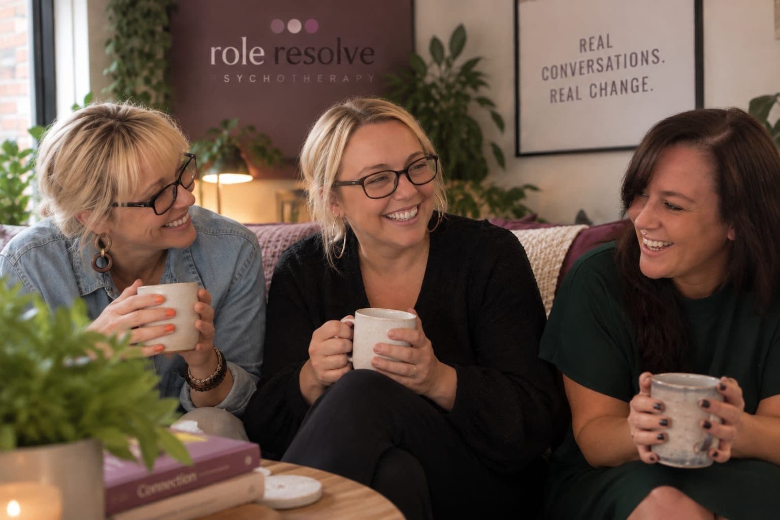 Three women laughing together over mugs of tea on a sofa at Role Resolve
